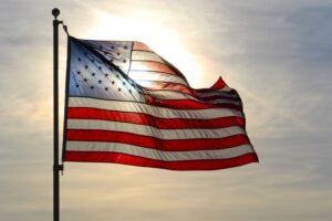 A sunlit American flag waves gracefully against a bright sky in Minnesota, USA.
